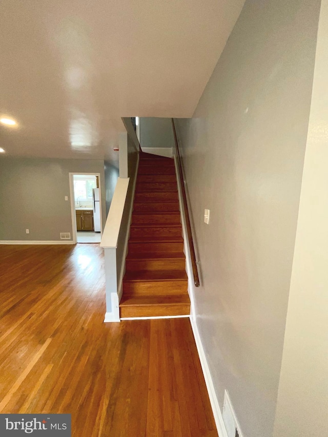 staircase featuring wood-type flooring and sink