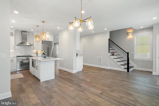 kitchen with a center island, white cabinets, hanging light fixtures, wall chimney exhaust hood, and stainless steel appliances