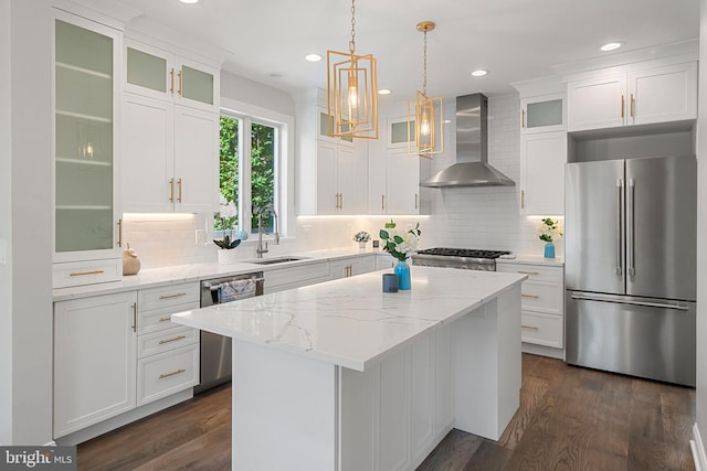 kitchen featuring appliances with stainless steel finishes, wall chimney exhaust hood, sink, dark hardwood / wood-style floors, and a kitchen island