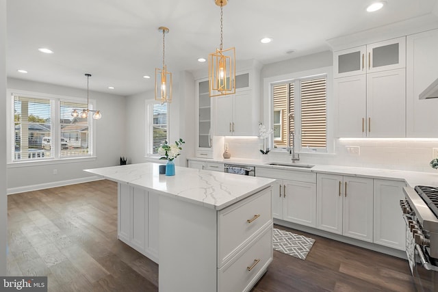 kitchen with pendant lighting, white cabinetry, a kitchen island, and sink