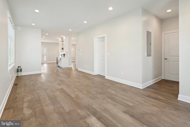 unfurnished living room featuring electric panel, light hardwood / wood-style flooring, and decorative columns