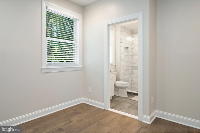 interior space featuring tiled shower, toilet, and hardwood / wood-style flooring