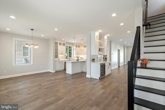 kitchen featuring dark hardwood / wood-style flooring, white cabinetry, hanging light fixtures, and beverage cooler