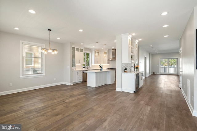 kitchen with wall chimney exhaust hood, white cabinetry, and hanging light fixtures