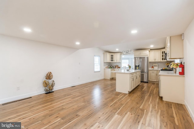 kitchen featuring a center island, light wood-type flooring, decorative light fixtures, and appliances with stainless steel finishes