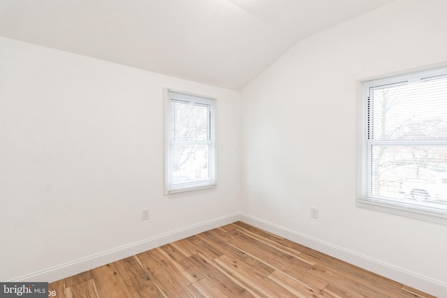 unfurnished room featuring a healthy amount of sunlight, vaulted ceiling, and light wood-type flooring