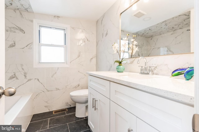 bathroom with vanity, toilet, and tile walls