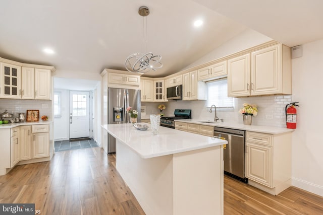 kitchen with appliances with stainless steel finishes, a center island, hanging light fixtures, and a healthy amount of sunlight