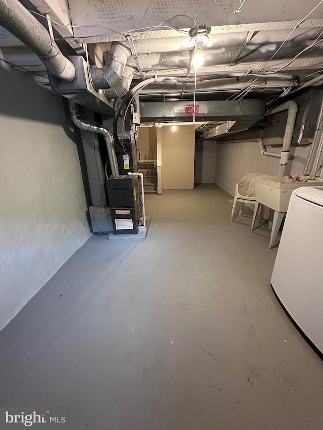 basement featuring sink, washer / dryer, and heating unit