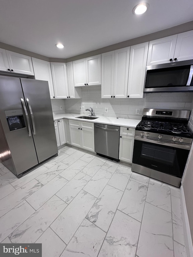 kitchen featuring stainless steel appliances, white cabinets, decorative backsplash, and sink