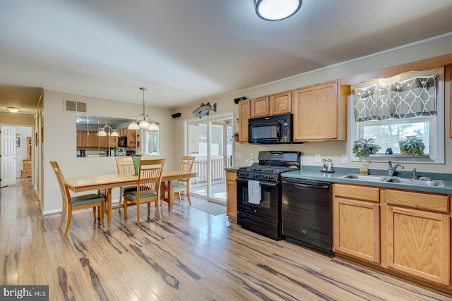 kitchen featuring light wood-type flooring, decorative light fixtures, a healthy amount of sunlight, and black appliances