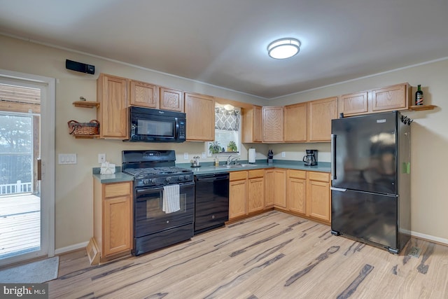 kitchen with light brown cabinets, black appliances, and light hardwood / wood-style floors