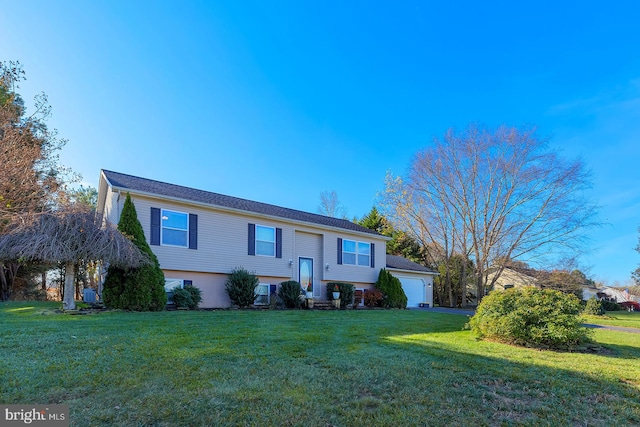 raised ranch featuring a front lawn and a garage