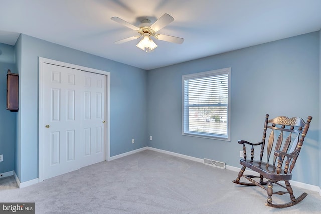 sitting room with ceiling fan and light colored carpet