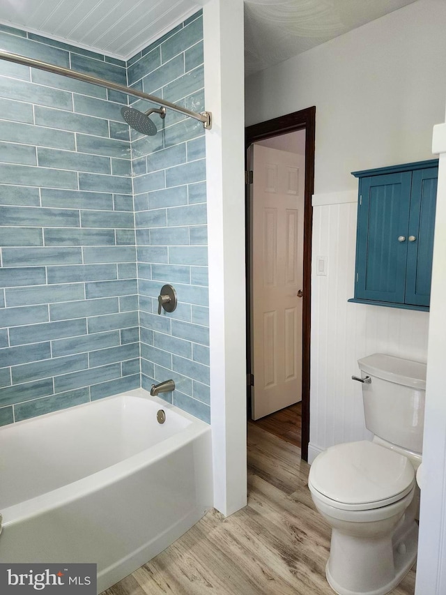 bathroom featuring tiled shower / bath combo, toilet, and wood-type flooring