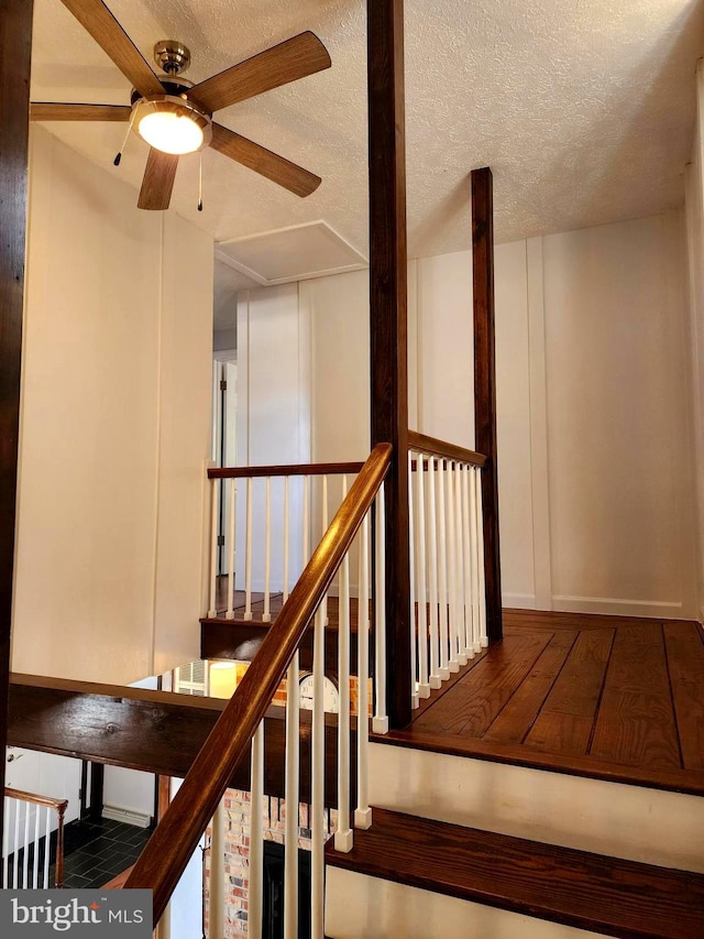 staircase featuring a textured ceiling and ceiling fan