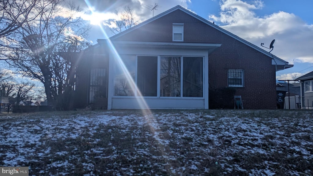 snow covered property with a sunroom