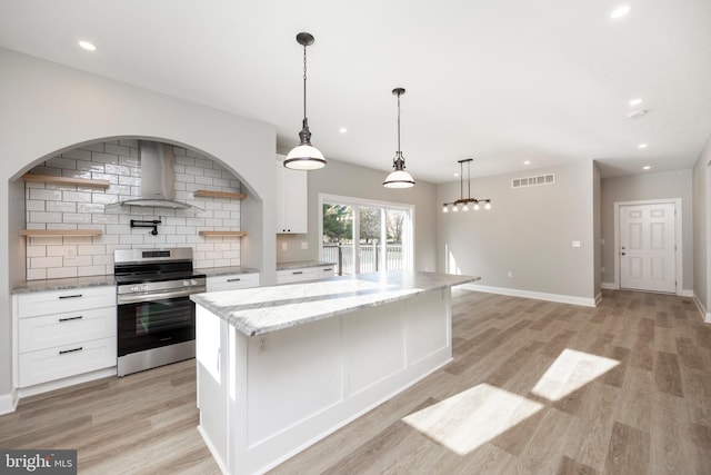 kitchen featuring white cabinets, light wood-type flooring, wall chimney range hood, and stainless steel stove