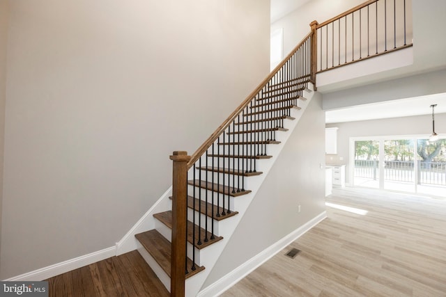 staircase with a chandelier and hardwood / wood-style flooring