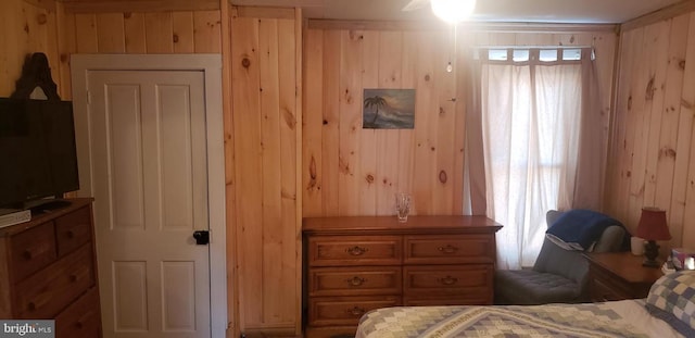 bedroom featuring wooden walls and multiple windows