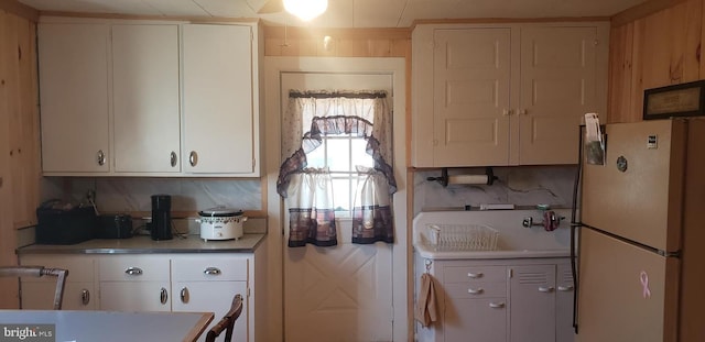 kitchen featuring decorative backsplash, white refrigerator, white cabinetry, and sink