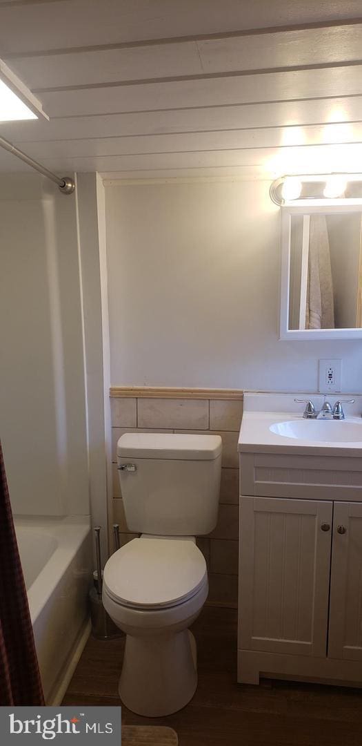 bathroom with hardwood / wood-style floors, vanity, tile walls, and toilet