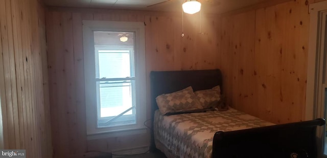 bedroom featuring ceiling fan and wood walls