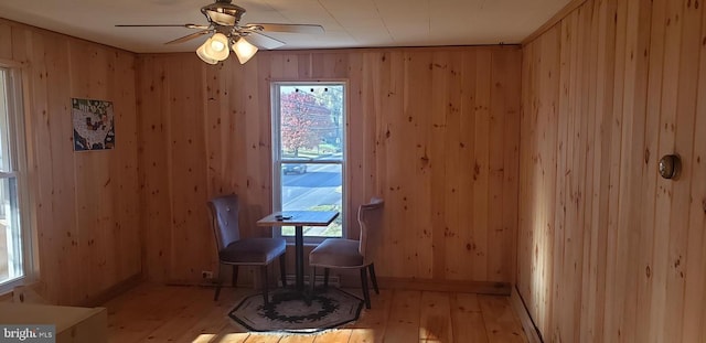 dining space featuring light hardwood / wood-style floors, a wealth of natural light, and wooden walls