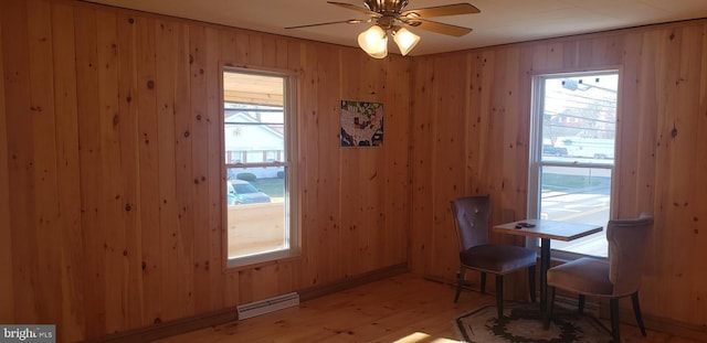 dining area with wooden walls, plenty of natural light, ceiling fan, and light hardwood / wood-style flooring