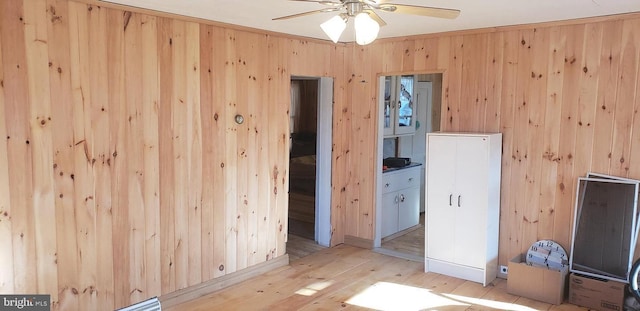 unfurnished room with wood walls, ceiling fan, and light hardwood / wood-style floors