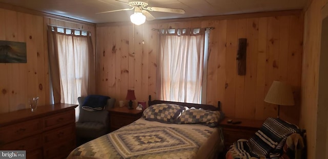 bedroom featuring ceiling fan and wooden walls