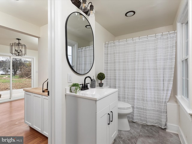 bathroom with vanity, wood-type flooring, an inviting chandelier, and toilet