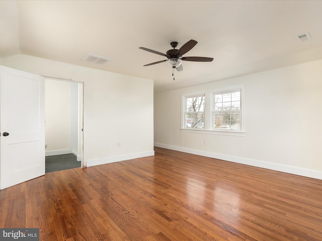 empty room with ceiling fan and dark hardwood / wood-style flooring