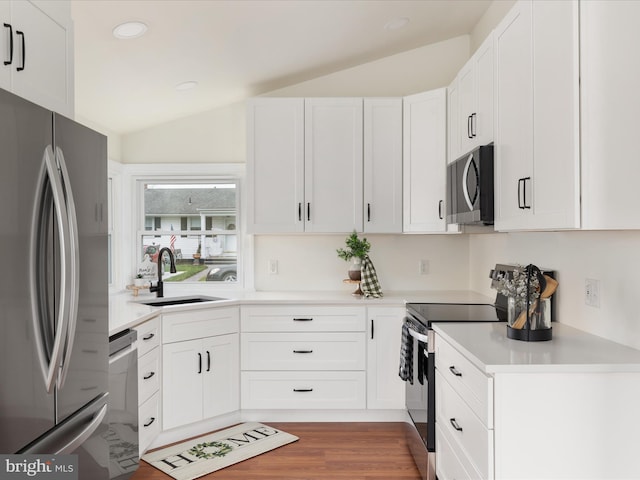 kitchen with stainless steel appliances, white cabinetry, and lofted ceiling