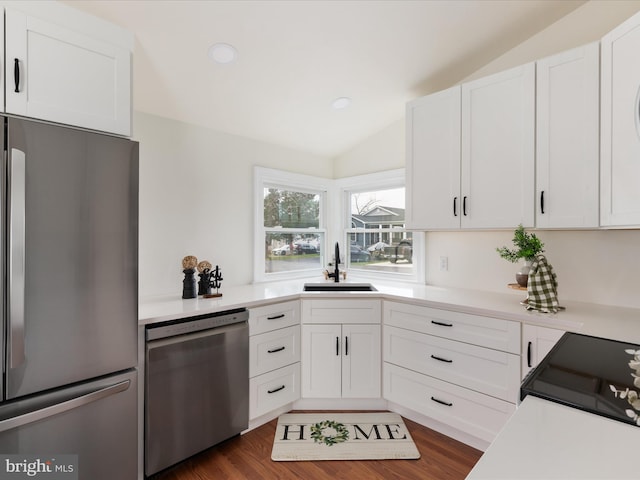 kitchen with lofted ceiling, sink, appliances with stainless steel finishes, white cabinetry, and dark hardwood / wood-style floors