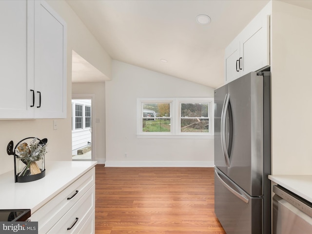 kitchen with lofted ceiling, stainless steel appliances, white cabinets, and light wood-type flooring