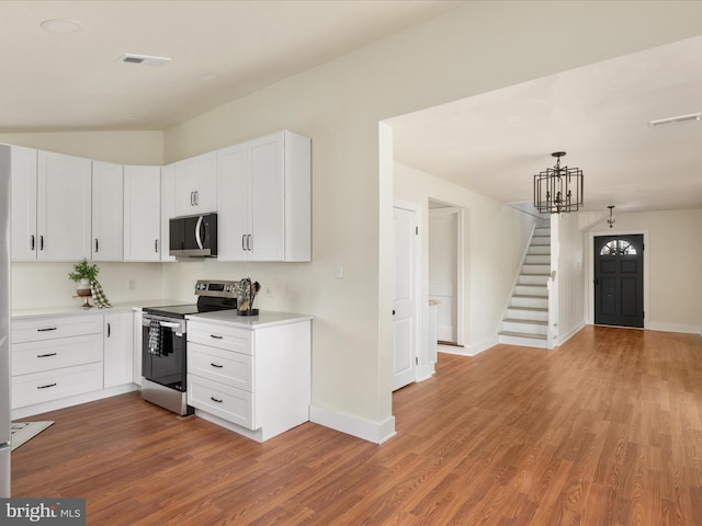 kitchen with white cabinetry, decorative light fixtures, a chandelier, electric range, and hardwood / wood-style floors