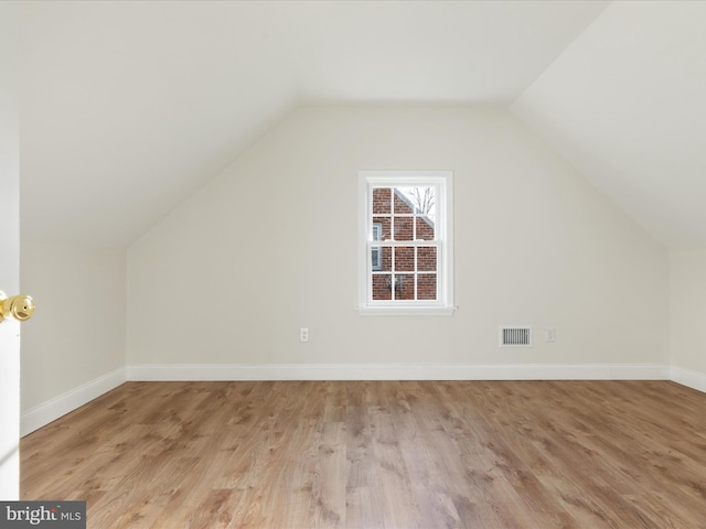 additional living space with light hardwood / wood-style floors and lofted ceiling