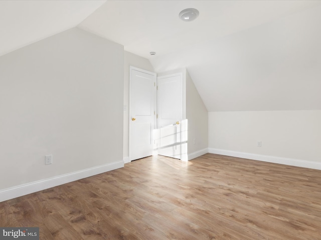 bonus room with light wood-type flooring and vaulted ceiling