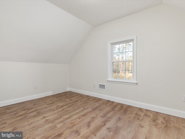 bonus room with light wood-type flooring and vaulted ceiling