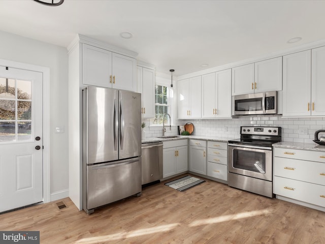 kitchen featuring white cabinetry, sink, light hardwood / wood-style flooring, and appliances with stainless steel finishes