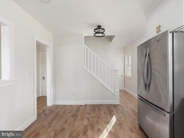 kitchen featuring white cabinets, light hardwood / wood-style flooring, and stainless steel refrigerator