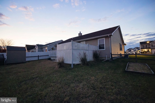 property exterior at dusk featuring a lawn and a shed