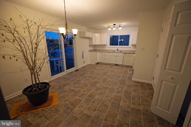 kitchen with white cabinetry, rail lighting, a notable chandelier, white dishwasher, and pendant lighting