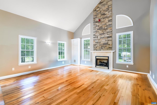 unfurnished living room with a fireplace, high vaulted ceiling, a healthy amount of sunlight, and light wood-type flooring