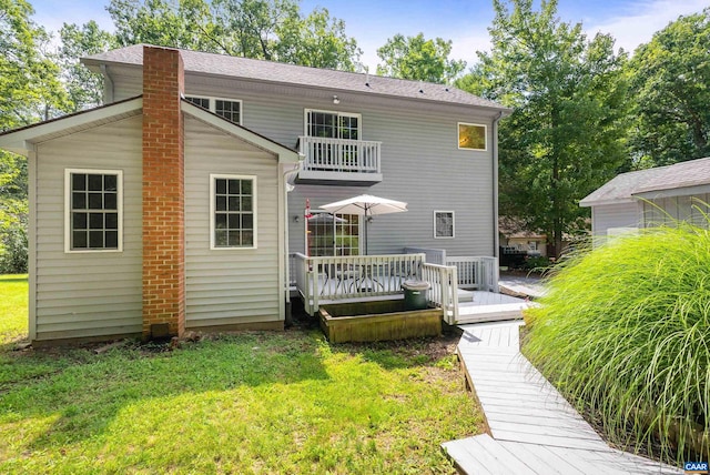 back of property with a lawn, a balcony, and a deck