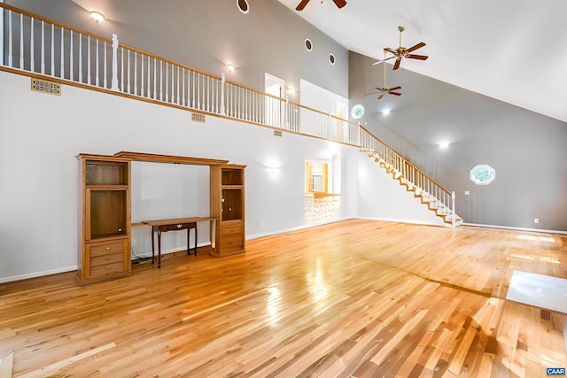 unfurnished living room featuring high vaulted ceiling and light wood-type flooring