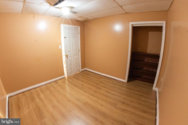 interior space with a drop ceiling, baseboards, and wood finished floors