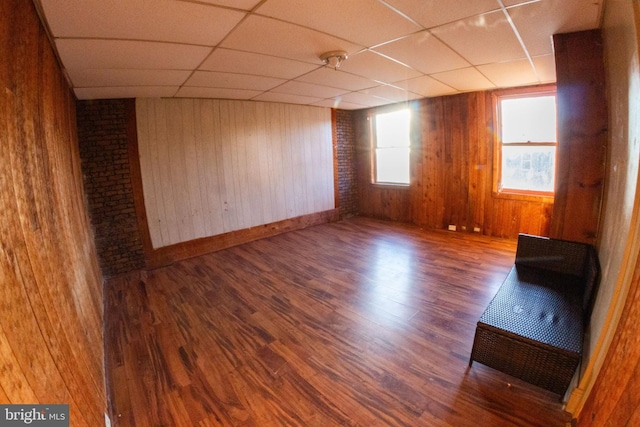 unfurnished room featuring a paneled ceiling, wood walls, and wood finished floors