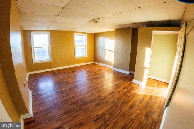 unfurnished room featuring a drop ceiling, wood finished floors, and baseboards